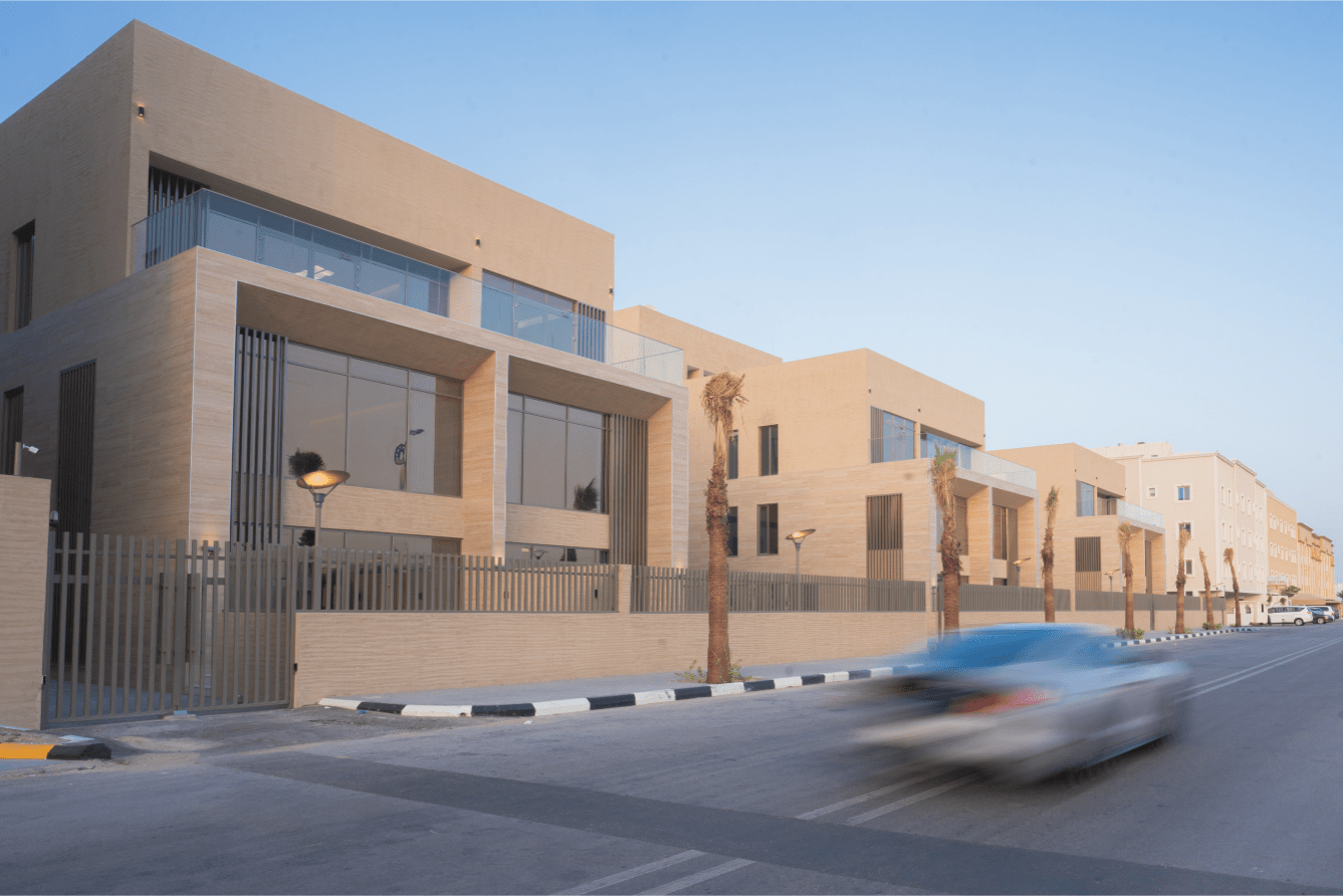 Modern gated residential complex with large glass windows and palm trees.